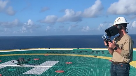 person in a hard hat flying a drone over sensors on the ocean to check for methane