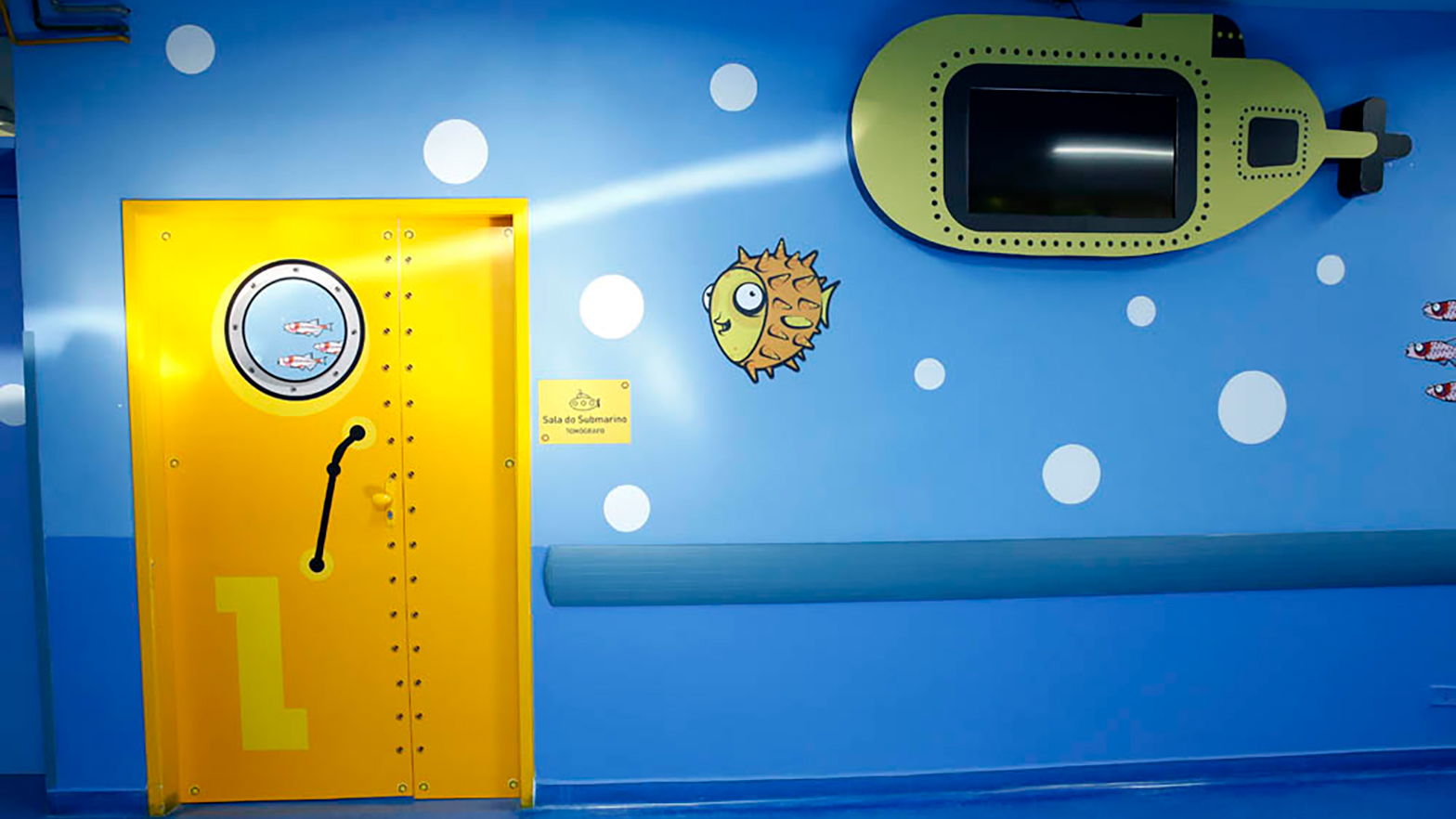 A cheerful porthole door leads to an undersea-themed radiology room.
