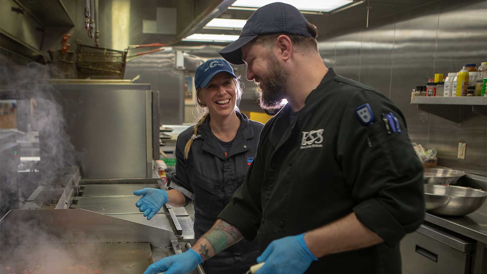 two chefs prepare meals over the kitchen stove
