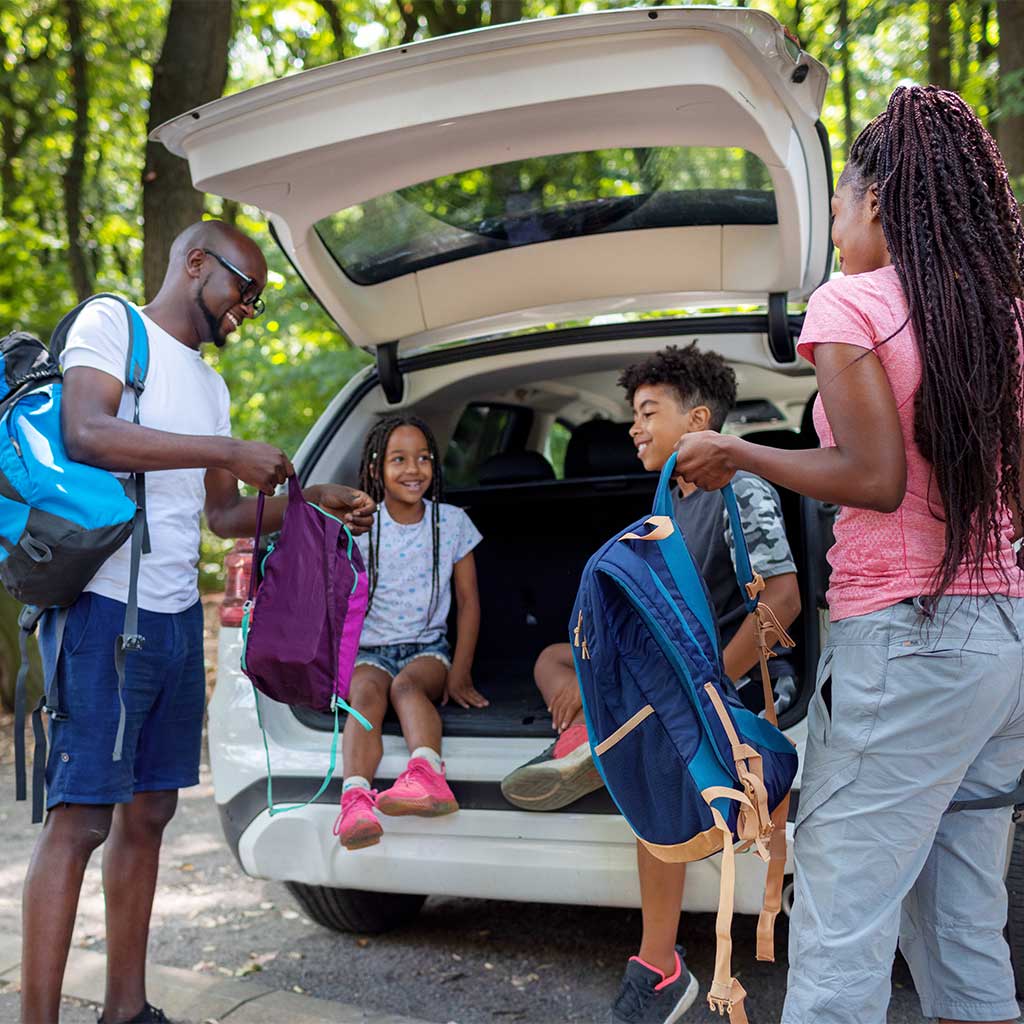A family put on their backpacks and head out in the sun