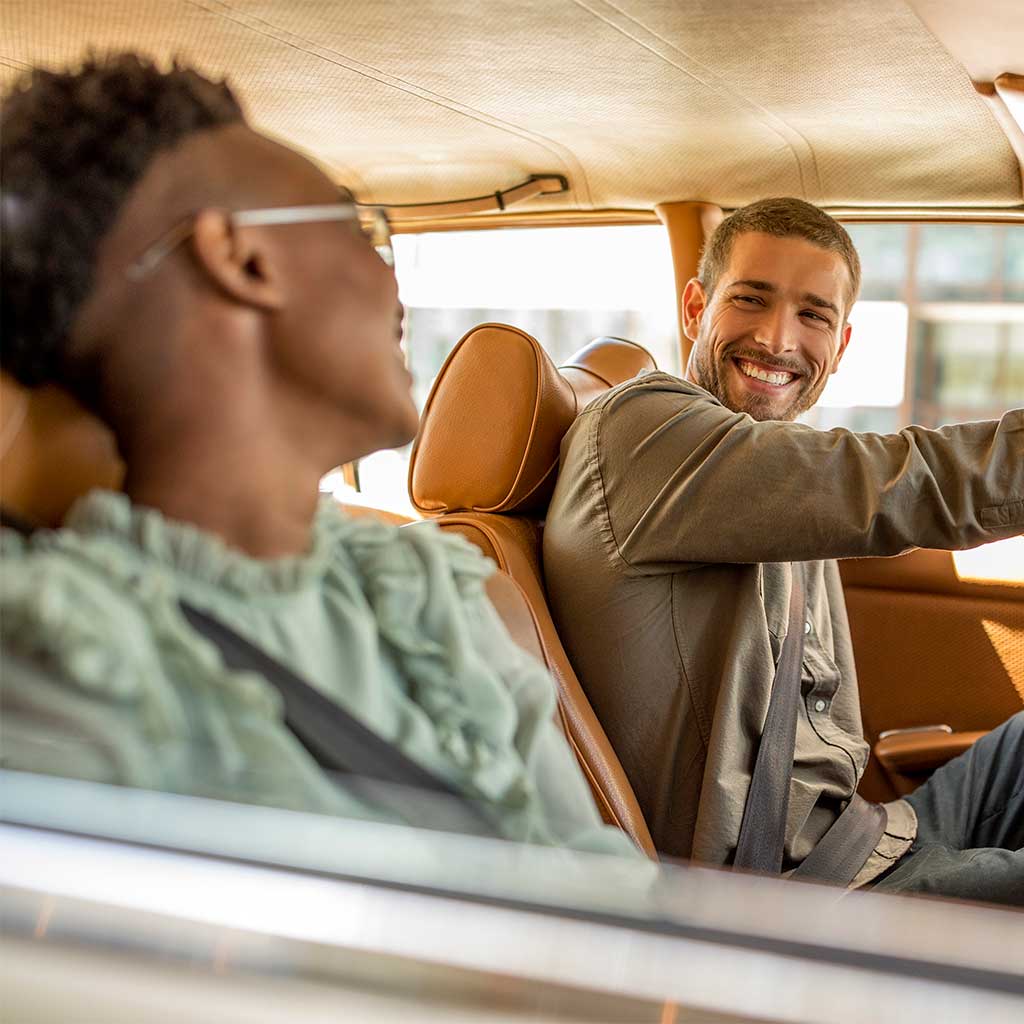 two guys go for a drive and smile at each other.