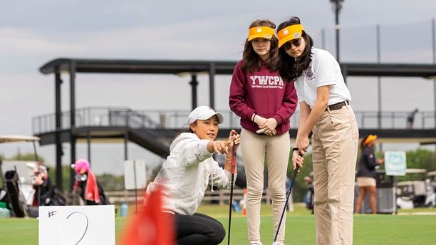 Students from the Young Women’s College Preparatory Academy hear putting instructions from a member of the University of Houston women’s golf team.