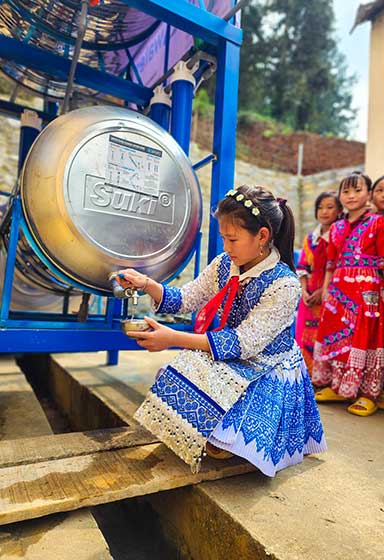 A girl in a dress takes water from a keg