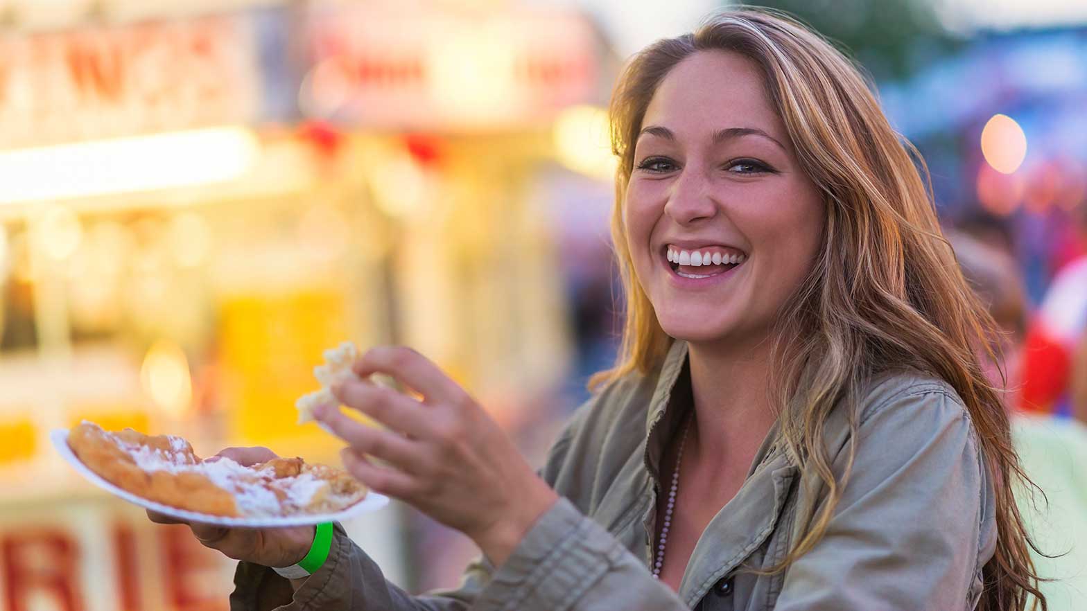 image of a woman eating funnel cake at a fair