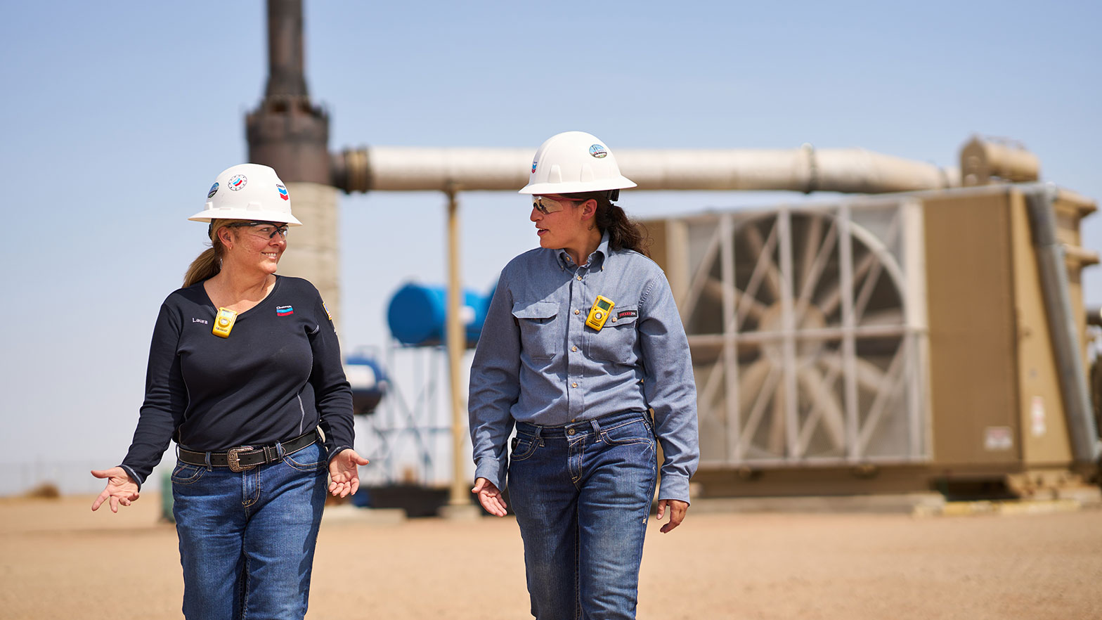 two women chevron employees walk and discuss the pipeline