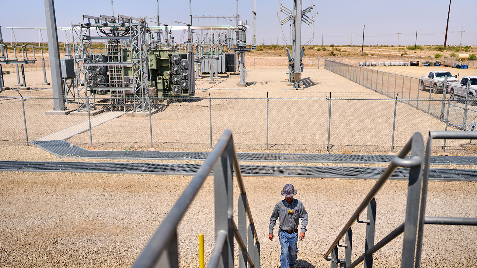 a chevron employees in a hard hat walks up the stairs near the permian basin structure