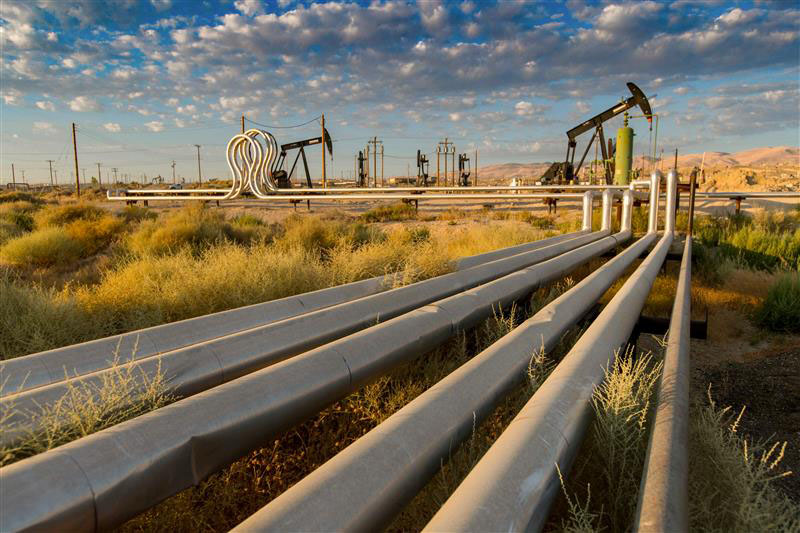A view of steam expansion pipes and loops with pumpjacks in the background at Kern River Field.