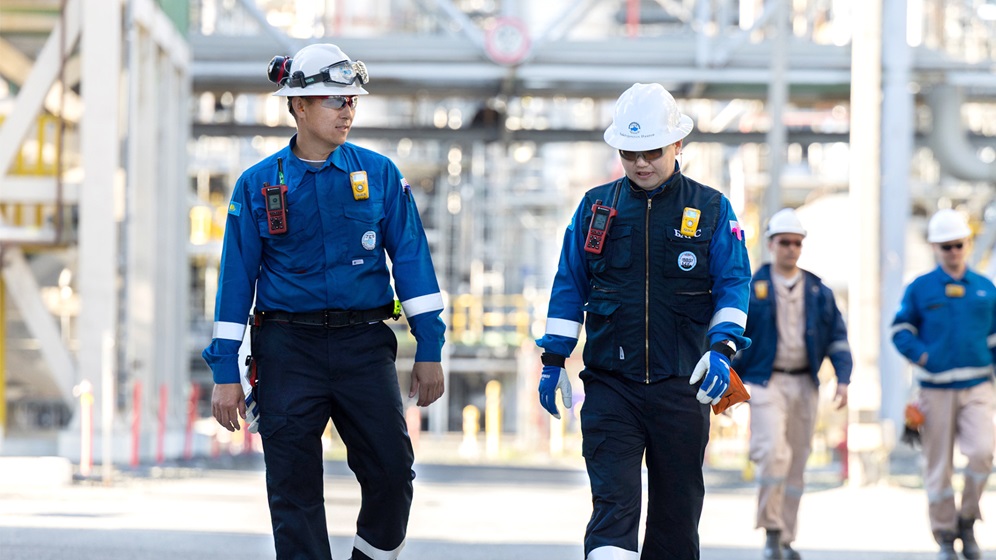 Employees walking in front of a refinery