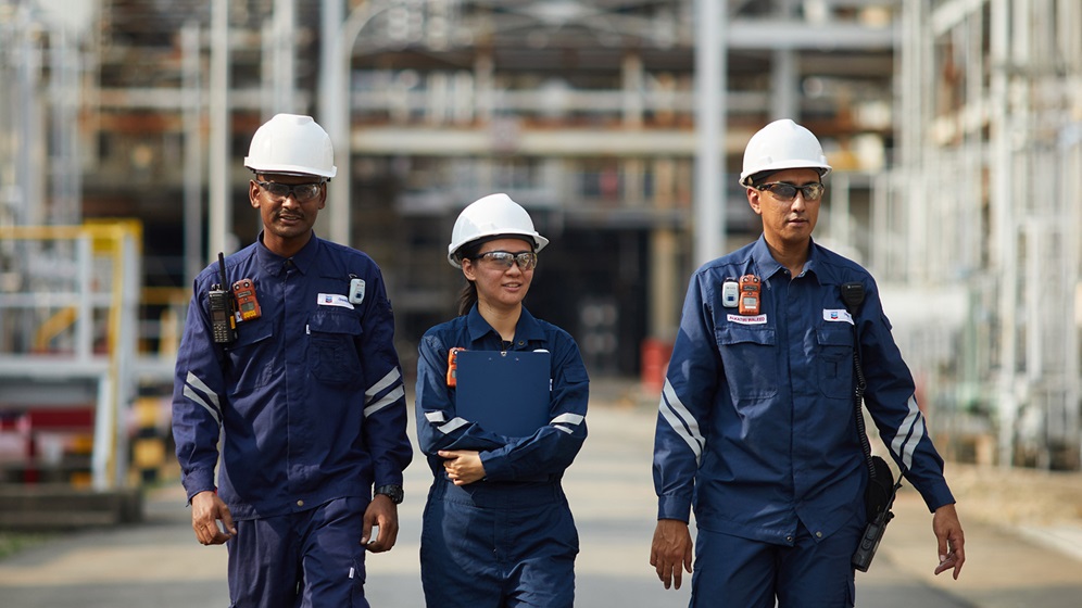 Three workers walking through a Chevron Oronite Singapore Manufacturing Plant (SMP) and performing a maintenance inspection.